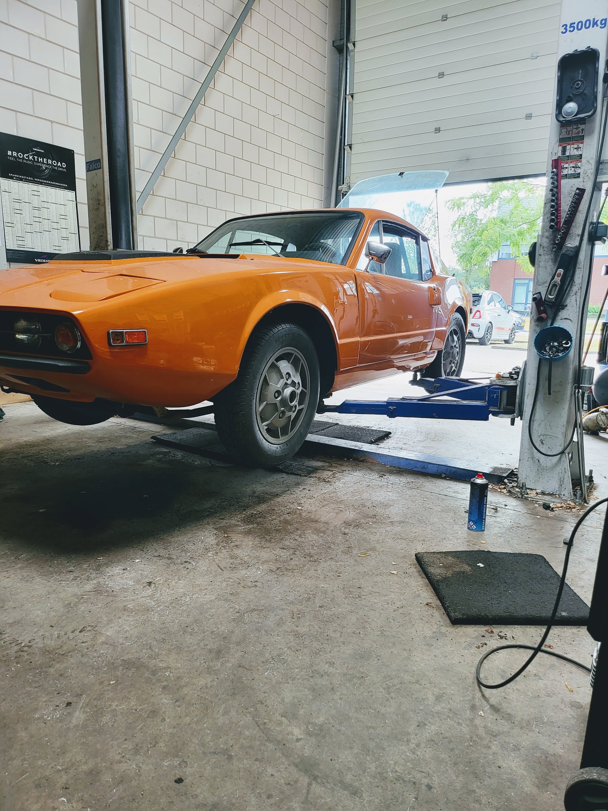 Een oranje Saab Sonett op de brug in de werkplaats